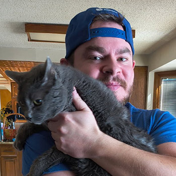 Cat sitter hanging out with his grey kitty helping him pose for the photo.