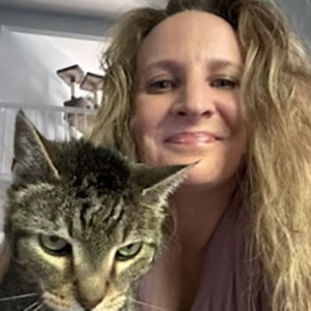 Happy cat loving sitter giving her kitten a snuggle and a smile.